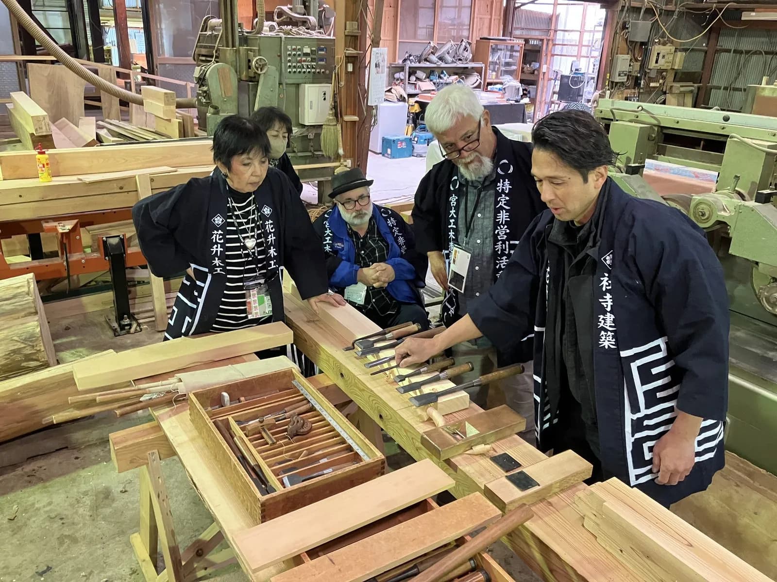 道具を囲む棟梁と研修生